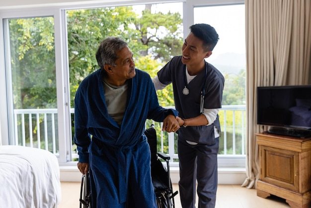 Des médecins divers aident les patients âgés à se lever du fauteuil roulant à la maison. Services médicaux, examens, visites à domicile, soins de santé, bien-être et mode de vie des personnes âgées, inchangés.